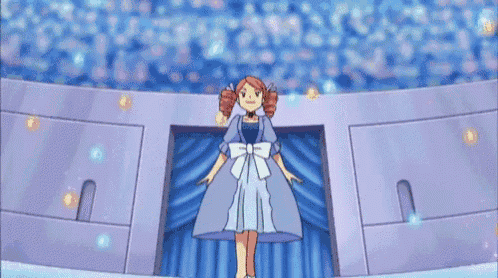 a girl in a blue dress is standing on a stage in front of a blue curtain .