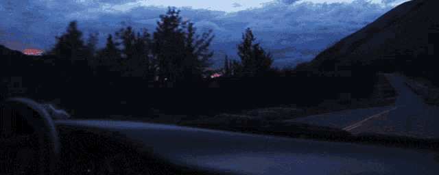 a car is driving down a road with trees on the side