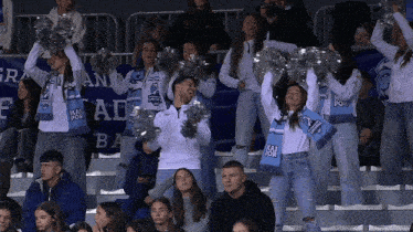 a group of cheerleaders wearing mai por scarves cheer on their team