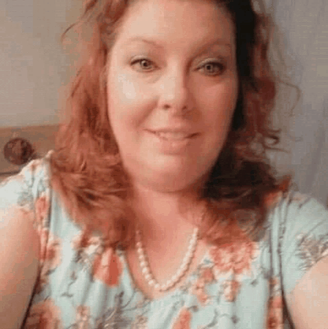 a woman is taking a selfie with a pearl necklace .