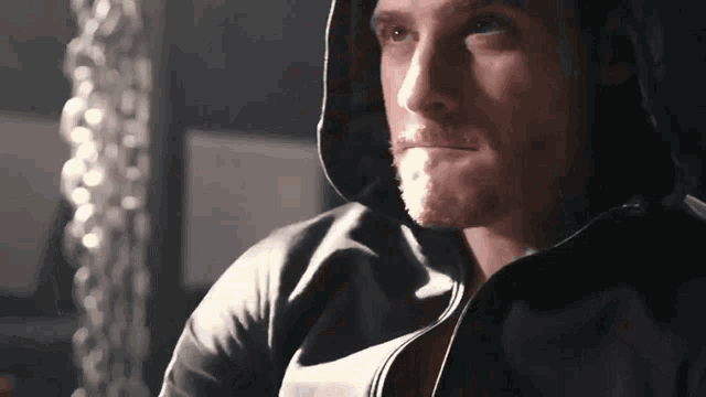 a man with a beard is wearing a black hooded jacket .