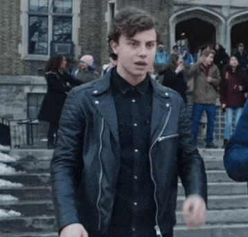a young man in a black leather jacket stands in front of a crowd