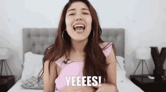a woman in a pink top says yeeees in front of her face