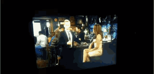 a man and woman are sitting at a bar talking to each other