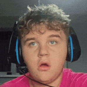 a man wearing headphones and a pink shirt is making a funny face