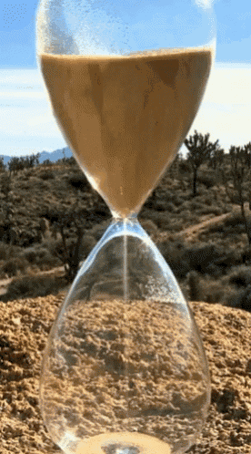 a hourglass filled with sand sits on top of a dirt hill