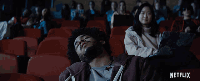 a man is sleeping in an auditorium with a netflix logo in the corner
