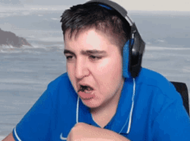 a man wearing headphones and a blue shirt is making a face