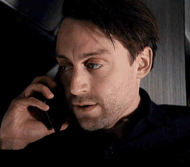 a man with a beard is talking on his cell phone