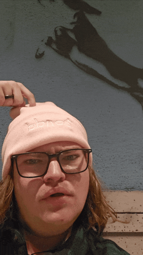 a man wearing glasses and a pink beanie with the word pbnce on it