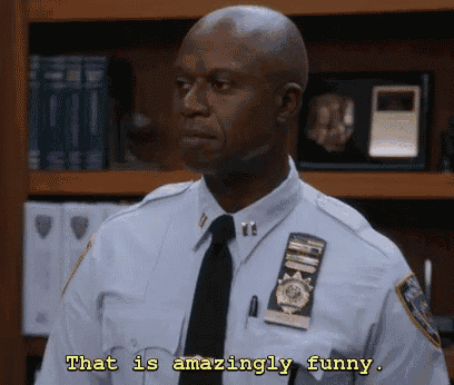 a police officer says " that is amazingly funny " while standing in front of a bookshelf