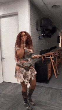 a woman with red hair is standing in a hallway wearing a dress and cowboy boots