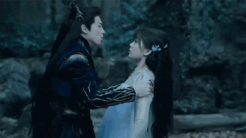 a man and a woman are kissing each other in a dark forest .