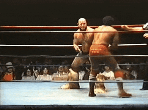 two men are wrestling in a ring and one of them is wearing red shorts that say fire on the back