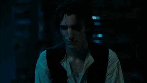 a man in a black vest and white shirt is looking down
