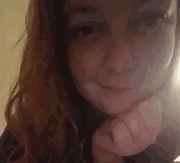 a woman with red hair is making a funny face with her hand on her chin .
