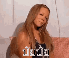 a woman with long blonde hair is sitting on a pink couch and making a face .