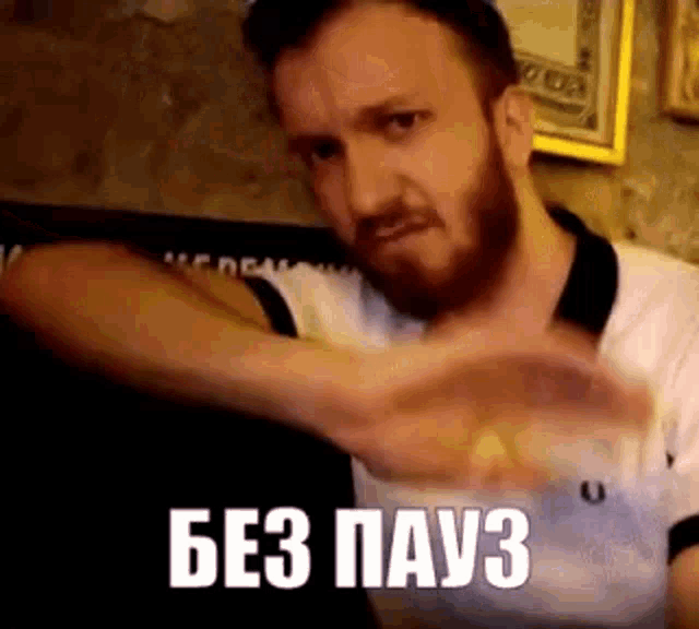 a man with a beard is making a funny face while sitting on a couch .