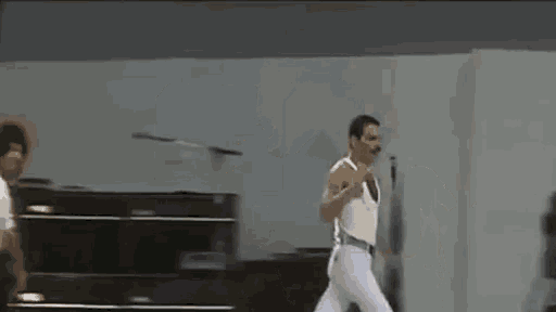 a man in a white tank top and white pants is dancing on stage .