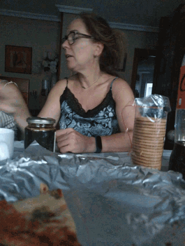 a woman sitting at a table with a bag of crackers