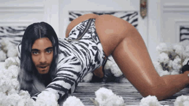 a woman in a zebra print bodysuit is laying on her stomach in front of flowers
