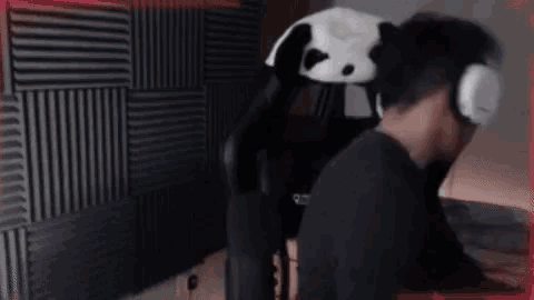a man is sitting in a chair with a stuffed panda bear on his head .