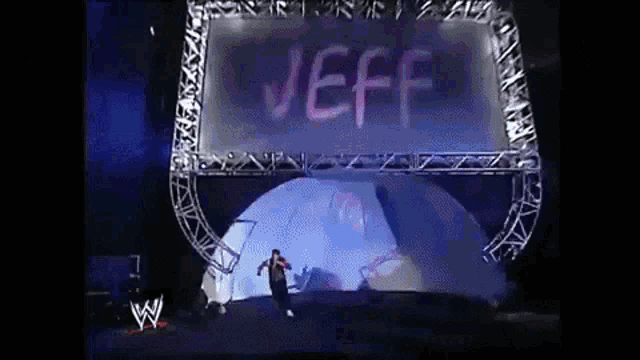 a man is standing on a stage in front of a large sign that says jeff .