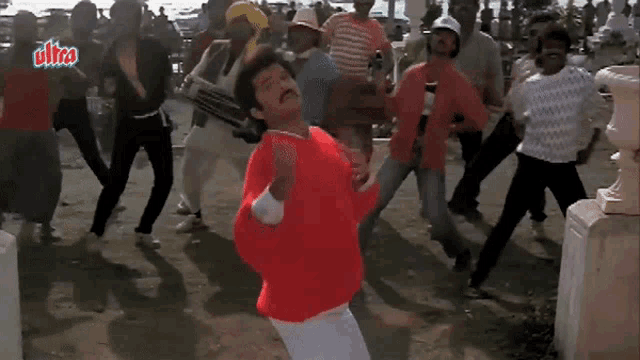 a man in a red shirt is dancing in front of a group of people .