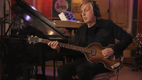 a man is playing a guitar in front of a beatles sign