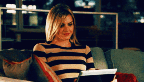 a woman is sitting on a couch using a tablet computer