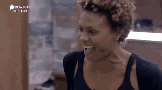 a woman with curly hair is smiling and laughing in a room .