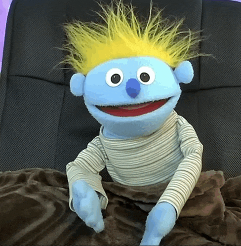 a blue puppet with a blue nose and yellow hair