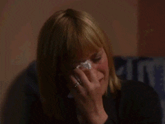 a woman is holding a tissue to her face while crying .