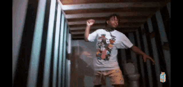 a man in a white t-shirt and yellow shorts is dancing in a bathroom .