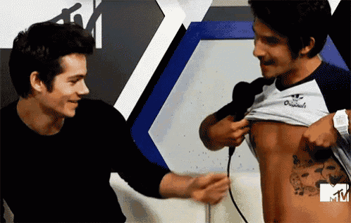 two men are standing next to each other and one of them has a tattoo on his stomach