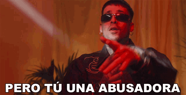 a man wearing sunglasses stands in front of a red curtain and says pero tu una abusadora