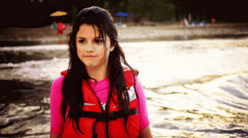 a girl wearing a red life jacket and a pink shirt is standing in the water