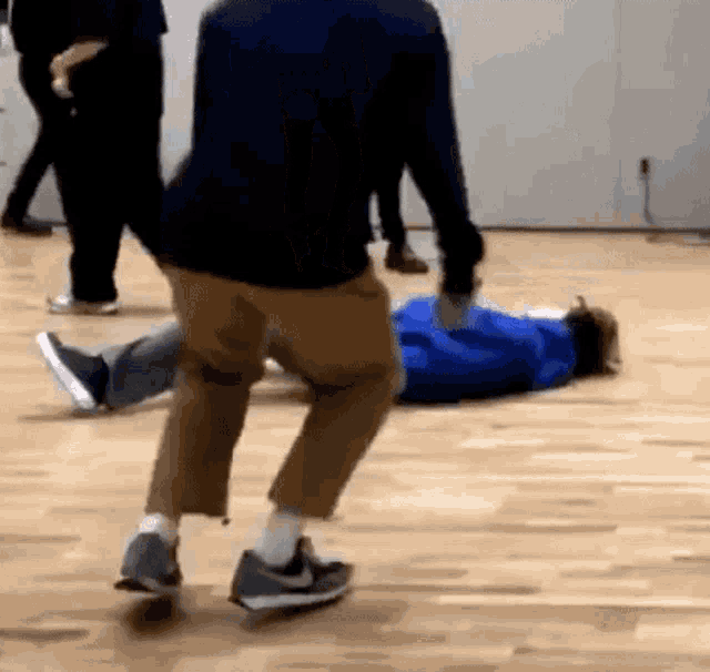 a group of people are dancing on a wooden floor while a person is laying on the floor .