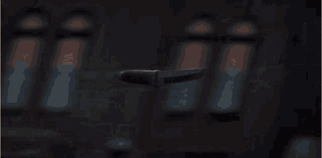 a person is holding a knife in their hand in a dark room
