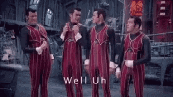a group of men in red jumpsuits are standing next to each other and talking in a room .