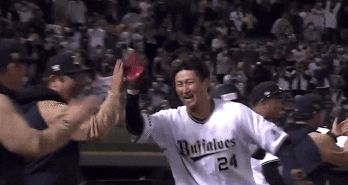 a baseball player is giving a high five to his teammates while wearing a number 24 jersey .