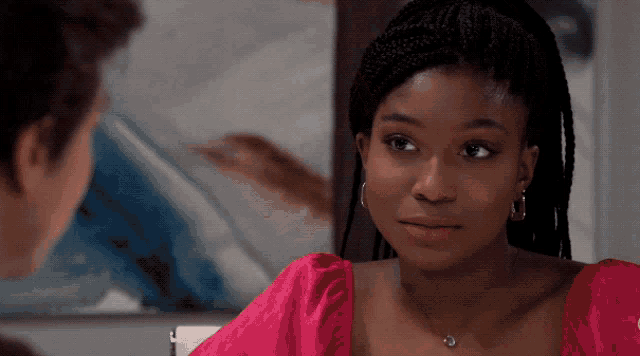 a woman wearing a pink top and earrings looks at a man
