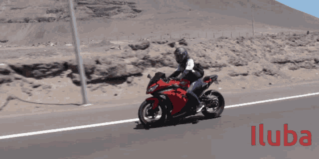 a person is riding a red motorcycle on a road with the word iluba in red