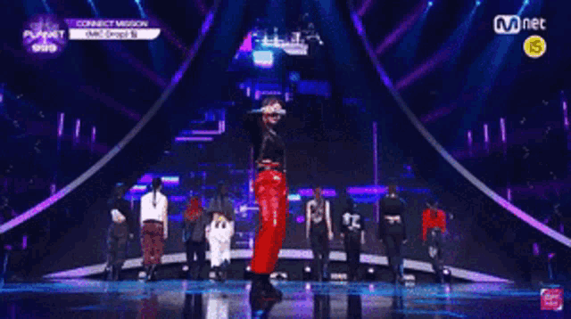 a group of people dancing on a stage with mnet written on the bottom of the screen