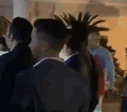 a group of people are standing in a room and talking to each other .