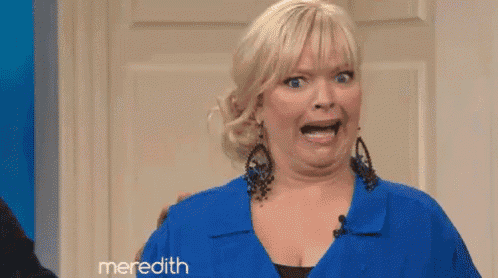 a woman is wearing a blue shirt and earrings and making a funny face .