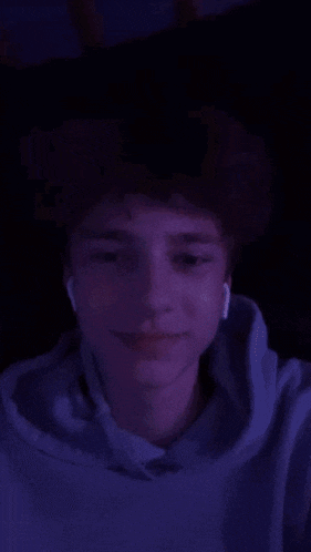 a man in a blue hoodie is covering his face with his hand .