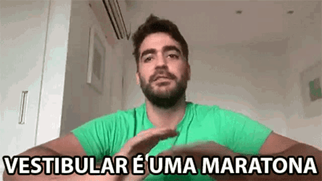 a man with a beard is wearing a green shirt and making a hand gesture .