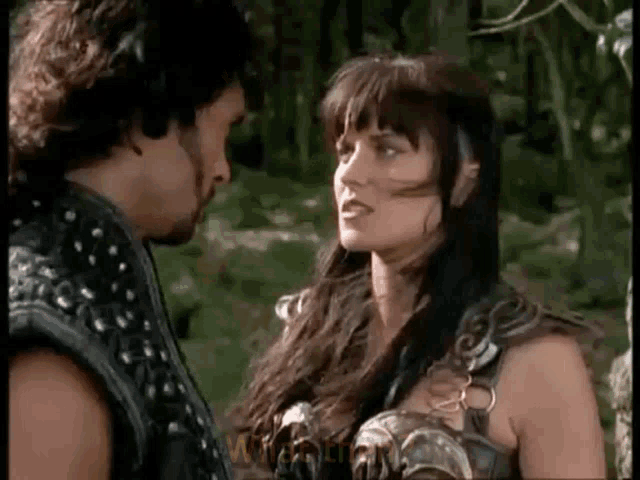 a man and a woman are standing next to each other in a forest .