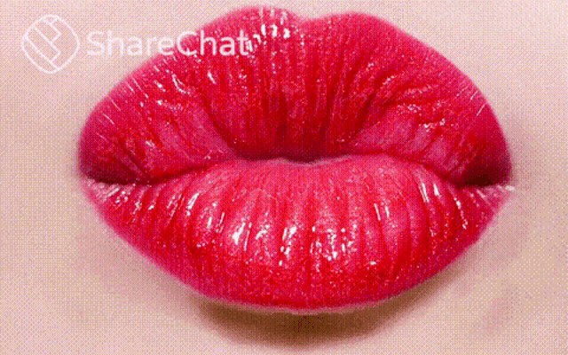 a close up of a woman 's red lips blowing a kiss .